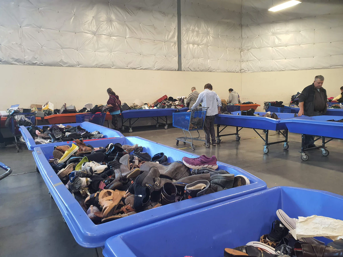 Everett Outlet Goodwill in Everett, Washington, featuring shoppers searching through bulk textile containers.