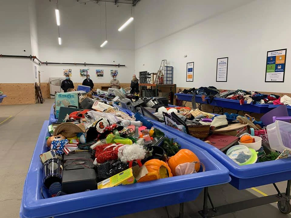 Goodwill As-Is Outlet and Donation Center in Medford, Oregon, featuring shoppers searching through bulk textile containers.
