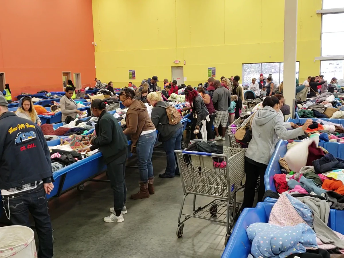 Goodwill - Brooklyn Park Outlet in Brooklyn Park, Minnesota, featuring shoppers searching through bulk textile containers.