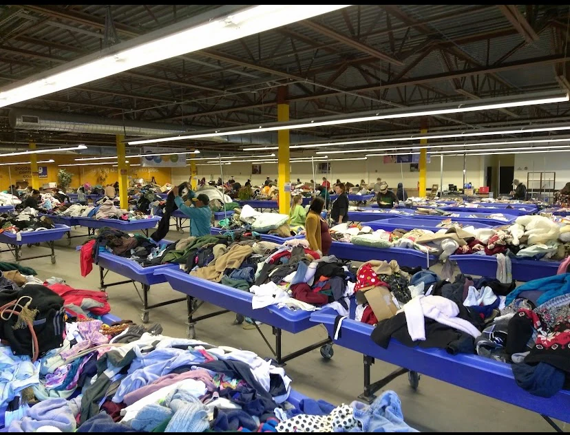 Goodwill Central Coast Outlet in Salinas, California, featuring shoppers searching through bulk textile containers.