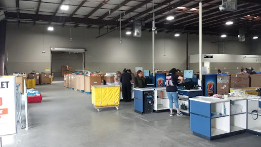 Goodwill Laredo Outlet in Laredo, Texas, featuring shoppers searching through bulk textile containers.