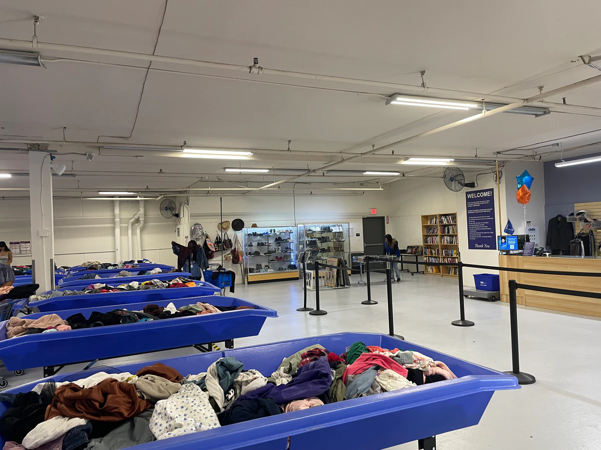 Goodwill Outlet and Donation Center in San Diego, California, featuring shoppers searching through bulk textile containers.