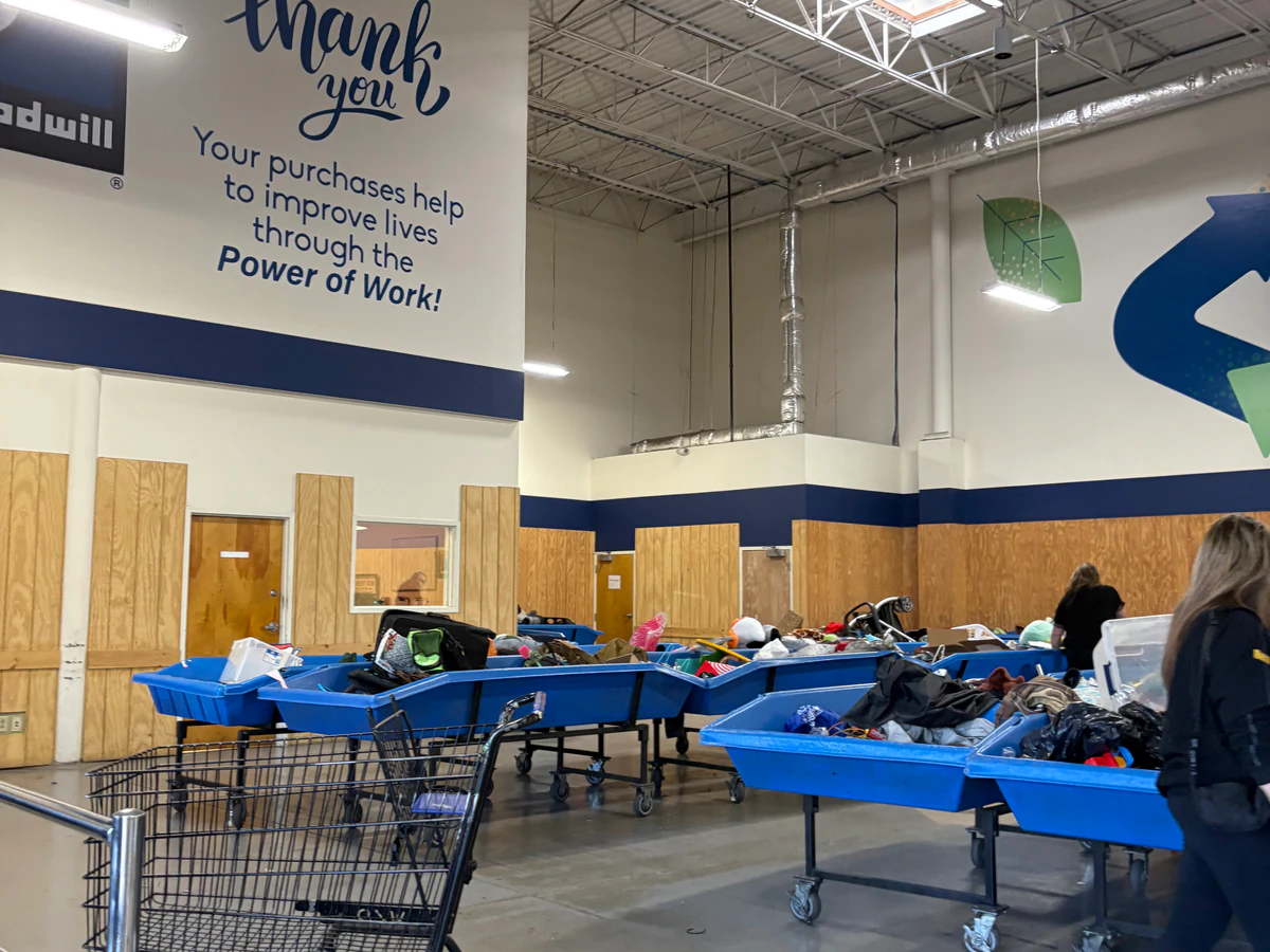 Goodwill Outlet in New Castle, Delaware, featuring shoppers searching through bulk textile containers.
