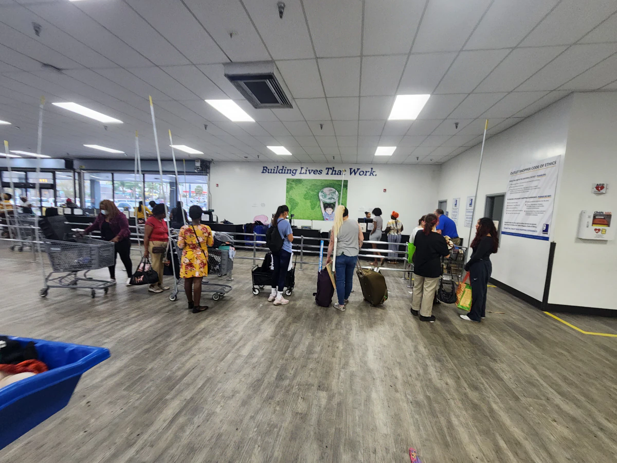 Goodwill - Pine Hills Outlet in Orlando, Florida, featuring shoppers searching through bulk textile containers.