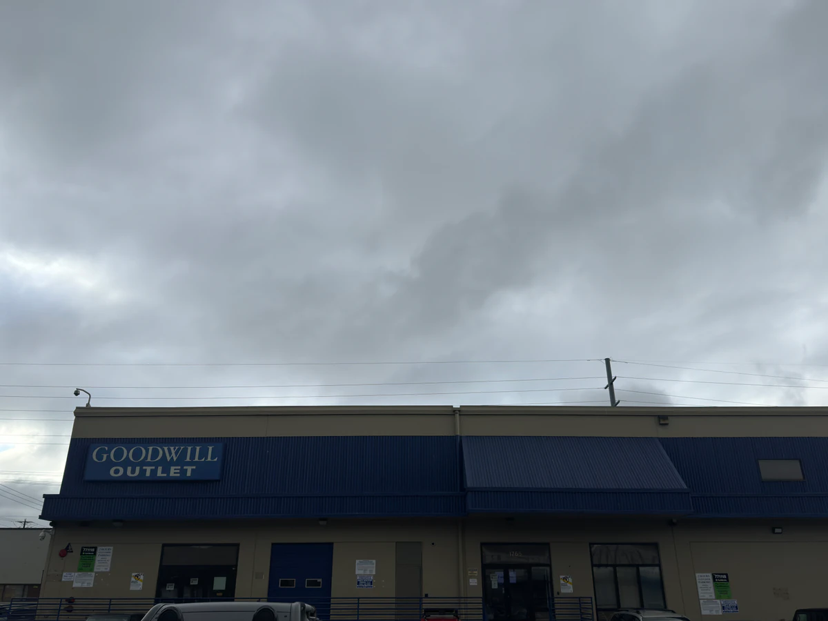 Seattle Outlet Goodwill in Seattle, Washington, featuring shoppers searching through bulk textile containers.